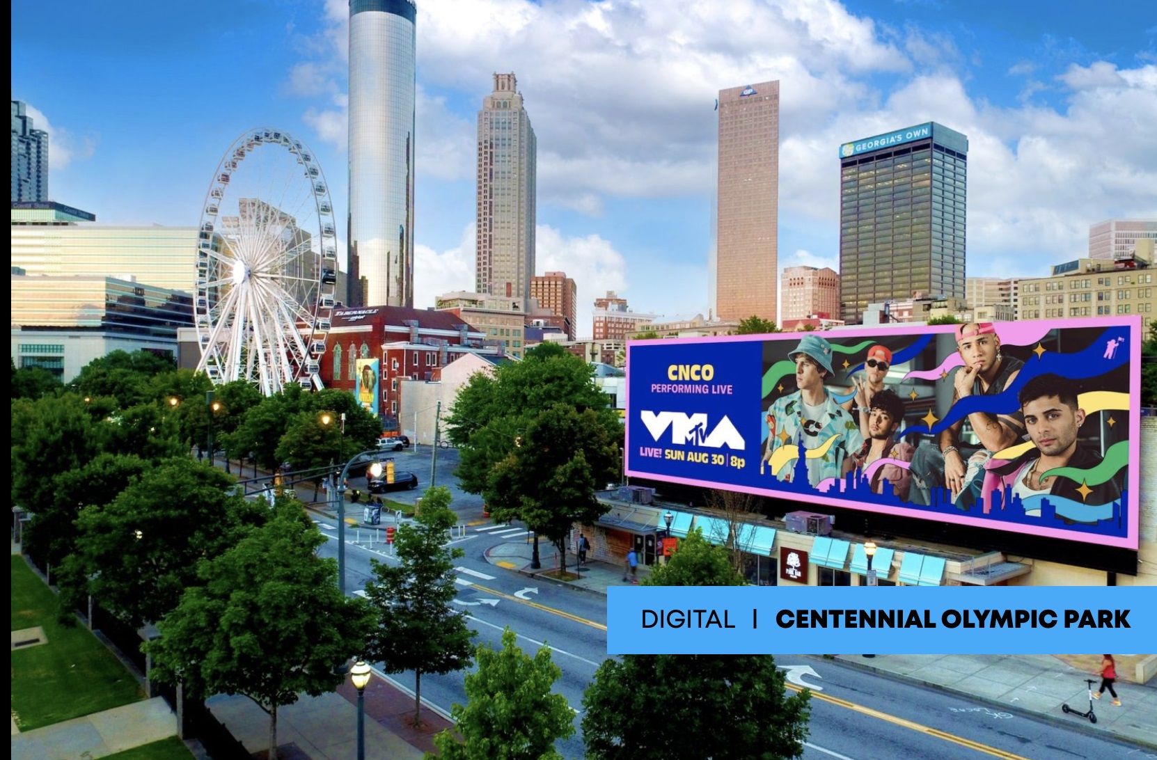 Digital ad for CNCO’s upcoming MTV performance on a billboard in Atlanta’s Centennial Olympic Park, with urban landmarks and clear blue sky.