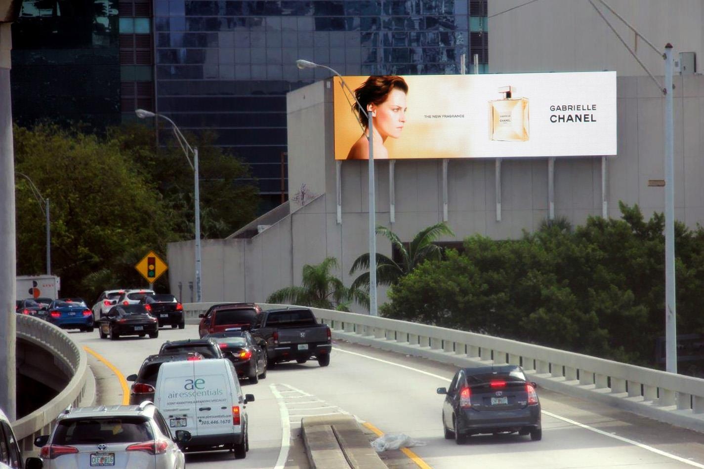 Highway scene with cars and a large digital billboard advertising Chanel's Gabrielle fragrance.
