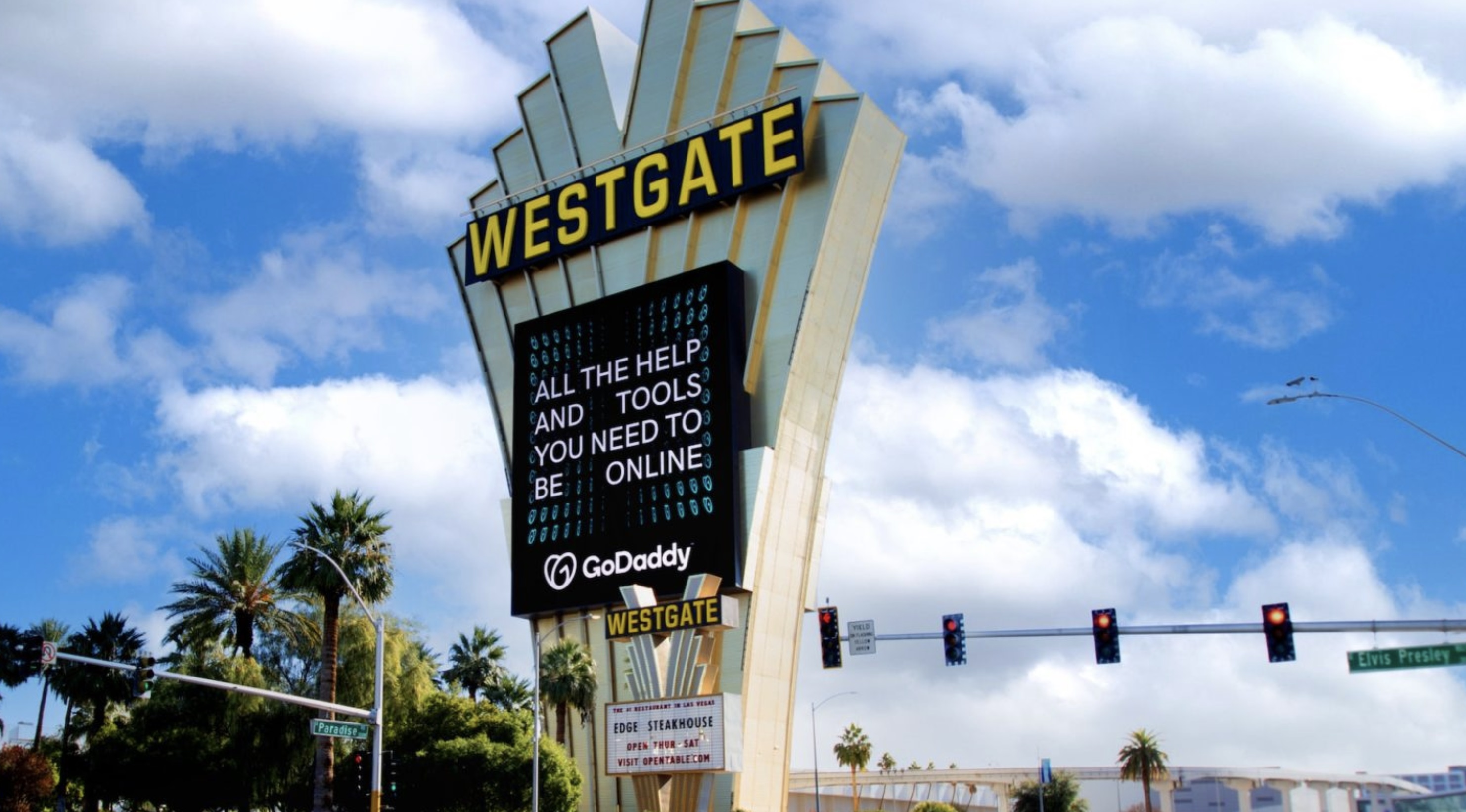 Westgate Las Vegas sign displaying a GoDaddy ad with the message, 'All the help and tools you need to be online,' against a backdrop of palm trees and a blue sky